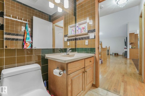 Full bathroom featuring tile walls, vanity, backsplash, and light wood-type flooring - 4720 150 Avenue, Edmonton, AB - Indoor Photo Showing Bathroom