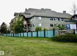 Multi-story building featuring light green siding and a dark shingle roof - 
