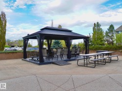Outdoor gazebo with a black metal frame and dark mesh privacy screens - 