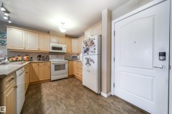 Kitchen with white appliances, light wood finish cabinetry, decorative backsplash, and light countertops - 