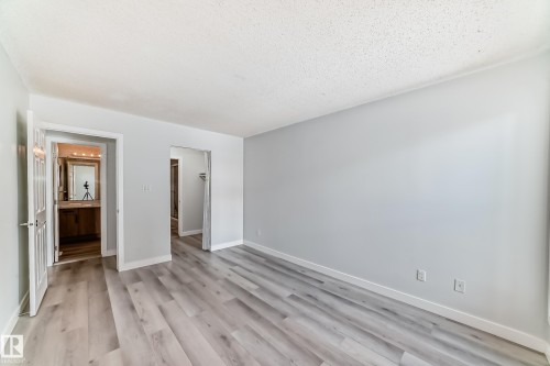 Unfurnished bedroom with light wood-type flooring, ensuite bathroom, and a textured ceiling - 23 1503 Mill Woods Road E, Edmonton, AB - Indoor Photo Showing Other Room