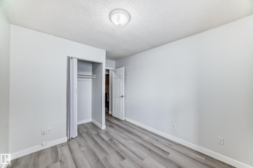 Unfurnished bedroom featuring a closet, a textured ceiling, and light wood finished floors - 23 1503 Mill Woods Road E, Edmonton, AB - Indoor Photo Showing Other Room