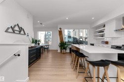 Kitchen with backsplash, wall chimney exhaust hood, open shelves, a breakfast bar, and white cabinetry. Moving into the dinning area. - 