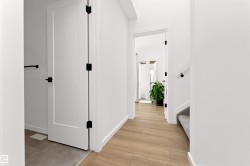 Corridor with stairs and light wood-style floors heading into the 2nd bedroom. - 
