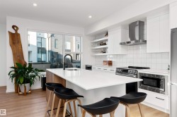 Kitchen with white cabinets, open shelves, SMART LG appliances, exhaust hood, quartz counters, tile backsplash, and modern cabinets. Enjoy! - 