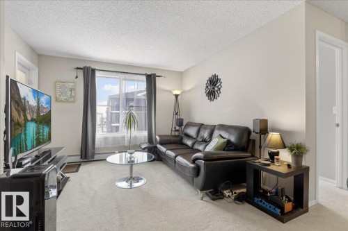 Carpeted living area featuring a textured ceiling - 305 12045 22 Avenue, Edmonton, AB - Indoor Photo Showing Living Room