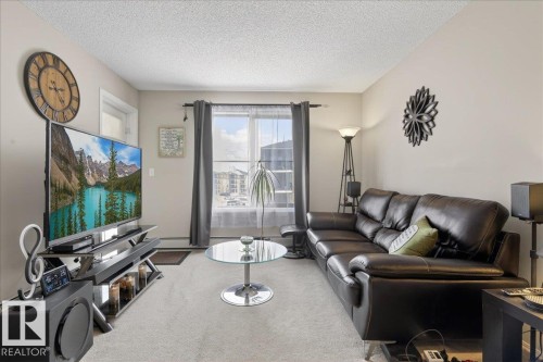 Living area with a textured ceiling and carpet flooring - 305 12045 22 Avenue, Edmonton, AB - Indoor Photo Showing Living Room
