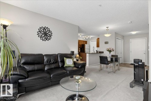 Living area featuring light carpet and a textured ceiling - 305 12045 22 Avenue, Edmonton, AB - Indoor Photo Showing Living Room