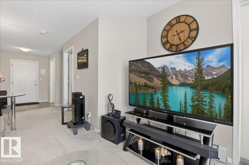 Living area with a textured ceiling and light carpet - 305 12045 22 Avenue, Edmonton, AB - Indoor Photo Showing Other Room