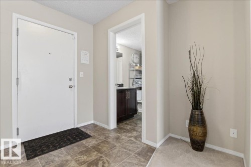 Foyer entrance with a textured ceiling and baseboards - 305 12045 22 Avenue, Edmonton, AB - Indoor Photo Showing Other Room