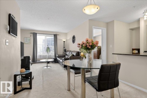 Dining room with light colored carpet and a textured ceiling - 305 12045 22 Avenue, Edmonton, AB - Indoor