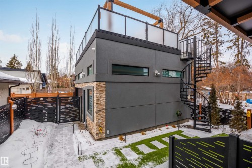 View of snowy exterior featuring stone siding, stucco siding, a gate, and a deck - 10038 142 Street, Edmonton, AB - Outdoor