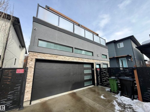 View of front facade featuring stone siding, a gate, stucco siding, and an attached garage - 10038 142 Street, Edmonton, AB - Outdoor