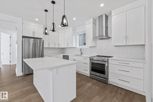 Kitchen featuring stainless steel appliances, tasteful backsplash, white cabinets, a kitchen island, and dark wood-style flooring - 10038 142 Street, Edmonton, AB - Indoor Photo Showing Kitchen With Upgraded Kitchen