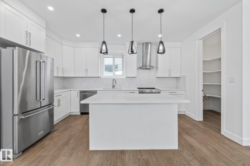 Kitchen with stainless steel appliances, backsplash, white cabinets, and a center island - 10038 142 Street, Edmonton, AB - Indoor Photo Showing Kitchen With Upgraded Kitchen