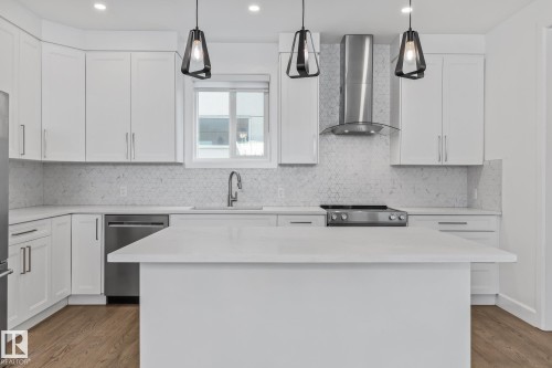 Kitchen featuring stainless steel appliances, white cabinets, light wood-style floors, and a center island - 10038 142 Street, Edmonton, AB - Indoor Photo Showing Kitchen With Upgraded Kitchen