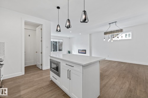 Kitchen with a kitchen island, light wood finished floors, stainless steel appliances, and white cabinets - 10038 142 Street, Edmonton, AB - Indoor