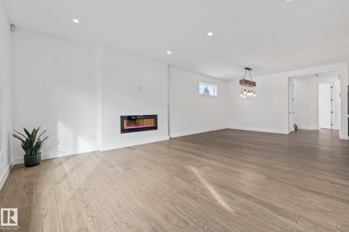 Unfurnished living room with light wood-style floors, recessed lighting, and a glass covered fireplace - 10038 142 Street, Edmonton, AB - Indoor Photo Showing Other Room With Fireplace