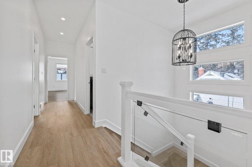 Hall featuring light wood-style floors, an upstairs landing, and suspended lighting - 10038 142 Street, Edmonton, AB - Indoor Photo Showing Other Room