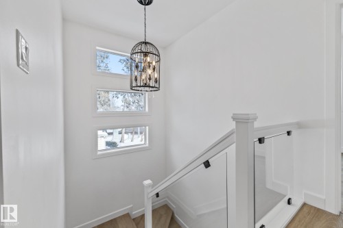 Stairway featuring hanging lights and wood finished floors - 10038 142 Street, Edmonton, AB - Indoor Photo Showing Other Room