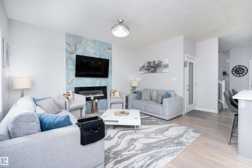 Living room featuring a fireplace, light wood-type flooring, and a textured ceiling - 43 1703 16 Avenue, Edmonton, AB - Indoor Photo Showing Living Room With Fireplace