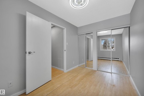 Unfurnished bedroom featuring multiple closets, a baseboard radiator, and light wood finished floors - 201 237 Woodvale Road W, Edmonton, AB - Indoor Photo Showing Other Room
