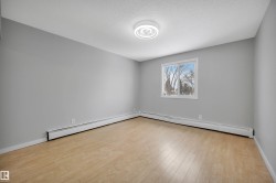 Unfurnished room featuring a baseboard heating unit, light wood finished floors, and a textured ceiling - 