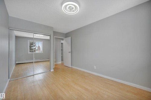 Unfurnished bedroom with a baseboard radiator, light wood-style flooring, and a closet - 201 237 Woodvale Road W, Edmonton, AB - Indoor Photo Showing Other Room