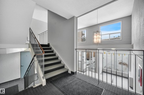 Staircase with a textured wall, carpet floors, a textured ceiling, and hanging lights - 201 237 Woodvale Road W, Edmonton, AB - Indoor Photo Showing Other Room