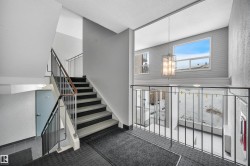 Staircase with a textured wall, carpet floors, a textured ceiling, and hanging lights - 