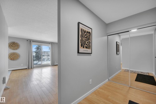 Corridor with light wood-style floors, a baseboard radiator, and a textured ceiling - 201 237 Woodvale Road W, Edmonton, AB - Indoor Photo Showing Other Room