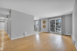 Unfurnished living room with baseboard heating, light wood-style floors, and a textured ceiling - 