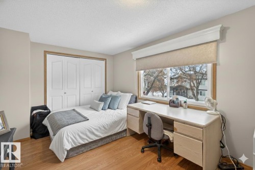 Bedroom featuring a closet, light wood-type flooring, a textured ceiling, and a desk - 14648 54 Street, Edmonton, AB - Indoor Photo Showing Bedroom