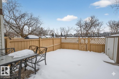 Yard covered in snow with a residential view, a fenced backyard, and outdoor dining area - 14648 54 Street, Edmonton, AB - Outdoor With Deck Patio Veranda