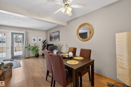 Dining space featuring a textured ceiling, light wood-style flooring, beam ceiling, and a ceiling fan - 14648 54 Street, Edmonton, AB - Indoor Photo Showing Dining Room
