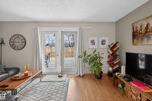 Living area featuring light wood-style flooring and a textured ceiling - 14648 54 Street, Edmonton, AB - Indoor