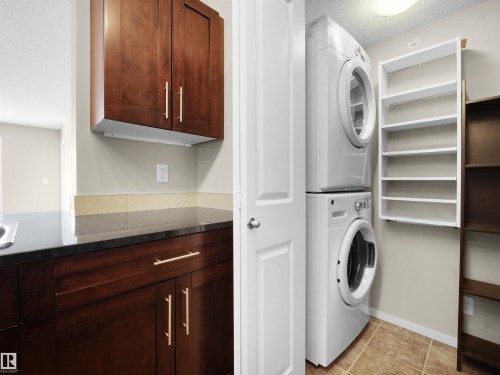 Laundry area featuring stacked washing machine and dryer and a textured ceiling - 422 5816 Mullen Place, Edmonton, AB - Indoor Photo Showing Laundry Room