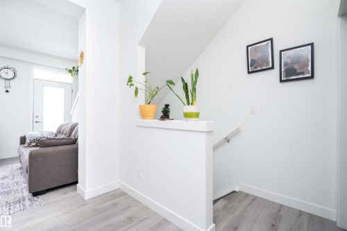 Hall with an upstairs landing and light wood-style floors - 24 2072 Wonnacott Way, Edmonton, AB - Indoor Photo Showing Other Room