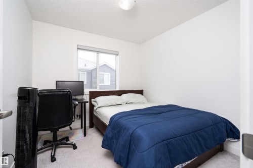 Bedroom featuring light carpet, a textured ceiling, and an office area - 24 2072 Wonnacott Way, Edmonton, AB - Indoor Photo Showing Bedroom