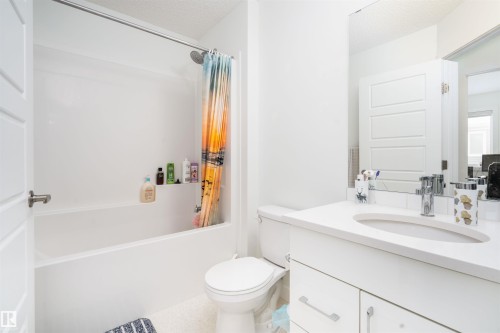 Bathroom with vanity, shower / bathtub combination with curtain, and a textured ceiling - 24 2072 Wonnacott Way, Edmonton, AB - Indoor Photo Showing Bathroom