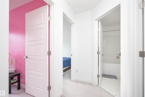 Hallway featuring a textured ceiling and light colored carpet - 24 2072 Wonnacott Way, Edmonton, AB - Indoor