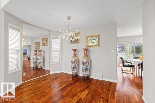 Dining space with a chandelier, dark wood-type flooring, and a textured ceiling - 11608 11A Avenue, Edmonton, AB - Indoor Photo Showing Other Room