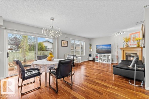 Dining room with a glass covered fireplace, a textured ceiling, wood finished floors, and a chandelier - 11608 11A Avenue, Edmonton, AB - Indoor With Fireplace