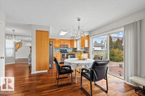 Dining room with a chandelier, dark wood-style floors, plenty of natural light, and a textured ceiling - 11608 11A Avenue, Edmonton, AB - Indoor Photo Showing Dining Room