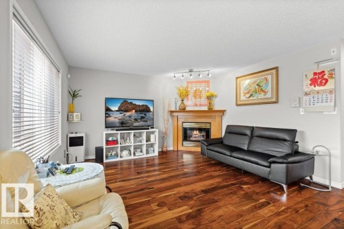 Living room with a glass covered fireplace, wood finished floors, and a textured ceiling - 11608 11A Avenue, Edmonton, AB - Indoor Photo Showing Living Room With Fireplace