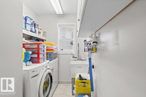Laundry area featuring light tile patterned flooring, a textured ceiling, washer and clothes dryer, and cabinet space - 11608 11A Avenue, Edmonton, AB - Indoor Photo Showing Laundry Room