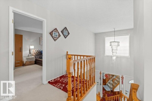 Hallway with an upstairs landing, a textured ceiling, carpet floors, and a chandelier - 11608 11A Avenue, Edmonton, AB - Indoor Photo Showing Other Room