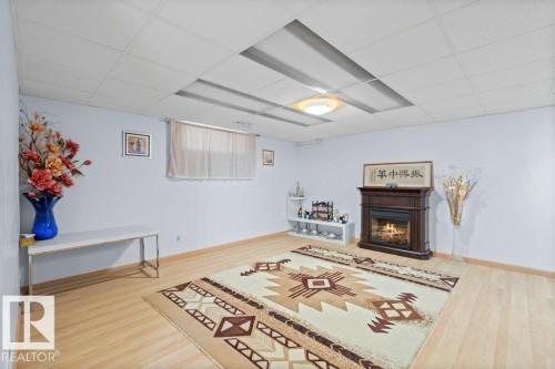 Sitting room with light wood-style flooring, a warm lit fireplace, and a drop ceiling - 11608 11A Avenue, Edmonton, AB - Indoor With Fireplace