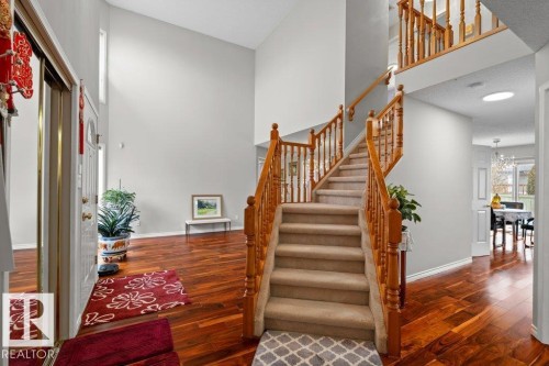 Staircase with wood finished floors, a chandelier, a towering ceiling, and a textured ceiling - 11608 11A Avenue, Edmonton, AB - Indoor Photo Showing Other Room