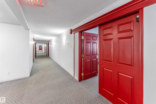 Hallway with light colored carpet and a textured ceiling - 107 9760 176 St, Edmonton, AB - Indoor Photo Showing Other Room